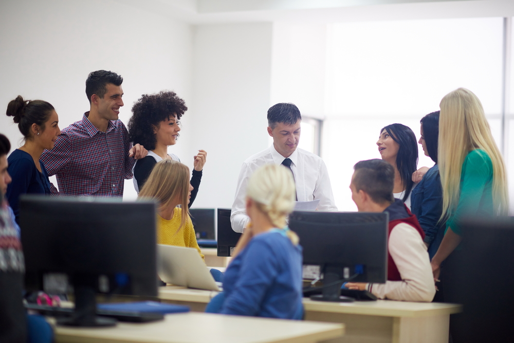 group of students with teacher in computer lab classrom learrning lessons,  get help and support